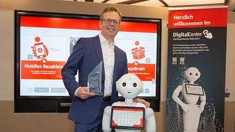 Vorstandsmitglied Dr. Bernd Hochberger mit dem Digital Award und Roboter Monaco Pepper
