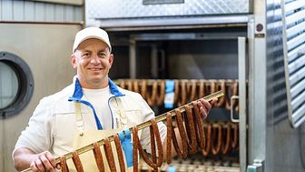 Mitarbeiter Waldemar Schulz von der Metzgerei Alsfelder Biofleisch nimmt Pfefferbeißer aus dem Räucherschrank. 