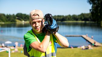 Simon, en av kommunens sommarjobbare sommaren 2020 arbetar vid ev av kommunens sjöar.