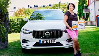 En stolt Eva poserar framför sin Volvo XC60.