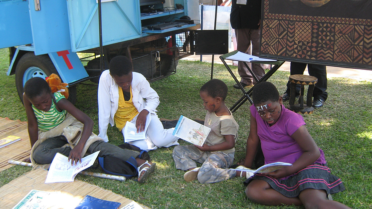 Fyra barn läser utanför ett av RLRDP:s mobila bibliotek i Zimbabwe. Foto: RLRDP