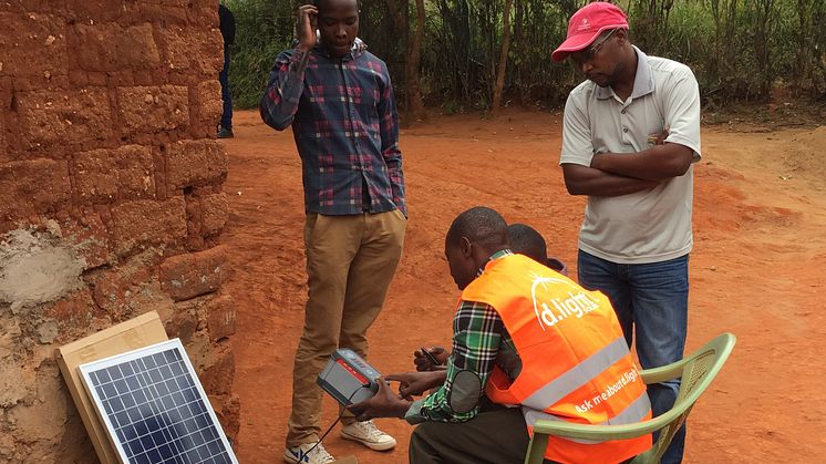 Installatör från d.light går igenom ett solar home system med en familj i utkanten av Nairobi, Kenya.