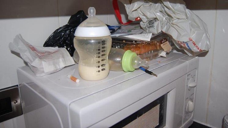 Two baby bottles, one containing congealed milk and a cigarette butt next to it
