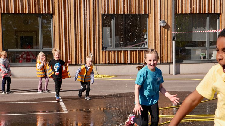 Glada barn på Västerstrandsskolan firar Generation Pep certifieringen ute på skolgården.