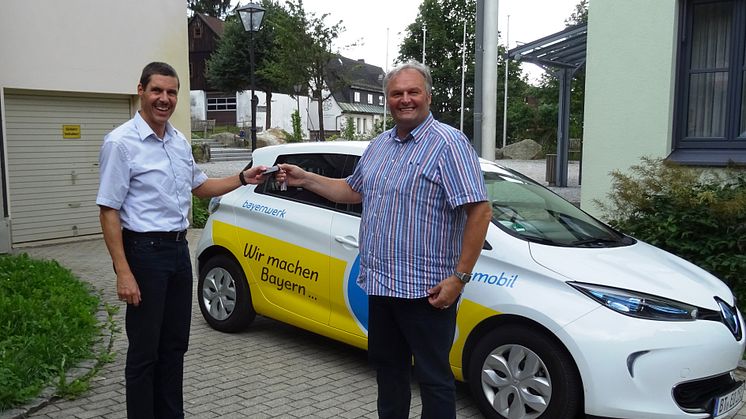 Bayernwerk-Kommunalbetreuer Burkhard Butz (l.) übergibt den Schlüssel eines voll elektrischen Renault Zoé aus dem Bayernwerk-Fuhrpark an Fichtelbergs Bürgermeister Georg Ritter (r.).