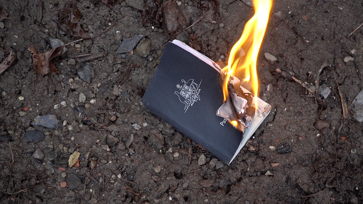 Anton Benois burning his Australian passport in the video work Spooky Campfire Stories from 2020.