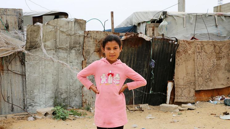 Ruba, 10 år, från Gaza står utanför det skjul som hon och hennes familj var tvungna att flytta till efter att deras hus blev bombat.