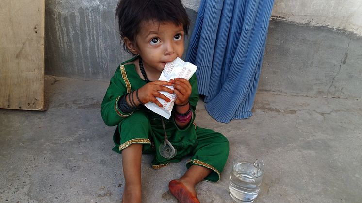 Tvååriga Marwa äter en Plumpy'nut (ett livsmedel baserat på jordnötter) på en av Medairs hälsokliniker i Kandaharprovinsen. Foto: ©Medair 
