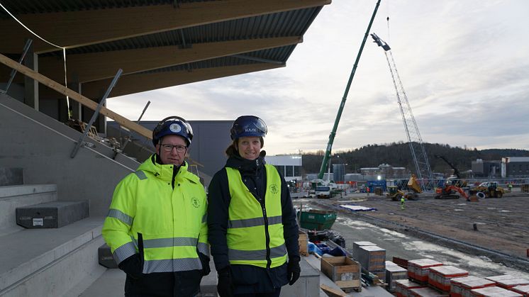 Projektledarna Anders Emilsson och Cecilia Wahlskog på den Östra läktaren av Rimnersvallen, i bakgrunden syns det första belysningstornet komma på plats.