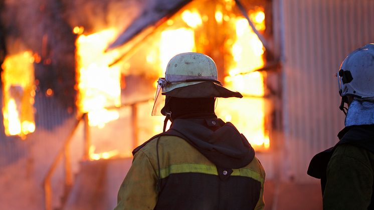 Brandman sedd bakifrån utanför brinnande hus, Istockphoto