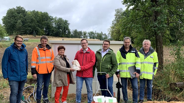 Vertreter der Gemeinde Brennberg nehmen an der neuen digitalen Ortsnetzstation in Hochaigen nachhaltige Blumensamen von der Bayernwerk Netz GmbH entgegen.
