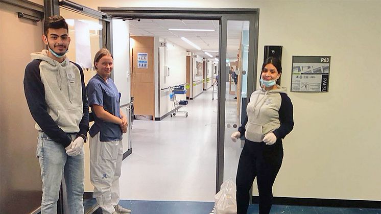 Haider Beden och Sara Akbari, elever på Thoren Business School Solna, skänker matlådor till personalen på Karolinska sjukhuset i Huddinge.