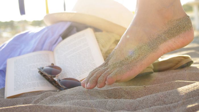 Woran in den Ferien am Strand kaum einer denkt: auch die Füße vor Sonnenbrand zu schützen und vor Fußpilz, der sogar im Sand lauern kann. Bild: Wellenhofer Designs | fotolia