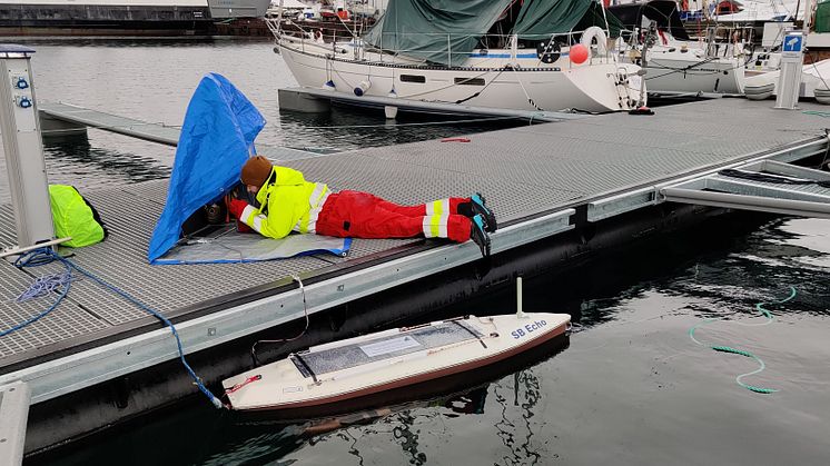 Muriel Dunn calibrating the echosounder on the sailbuoy in rainy weather (Photo: Håvard Buschmann/Akvaplan-niva).