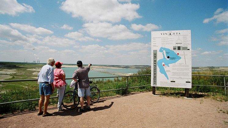 Besucher blicken auf den Störmthaler See - im Hintergrund das Kraftwerk Lippendorf 
