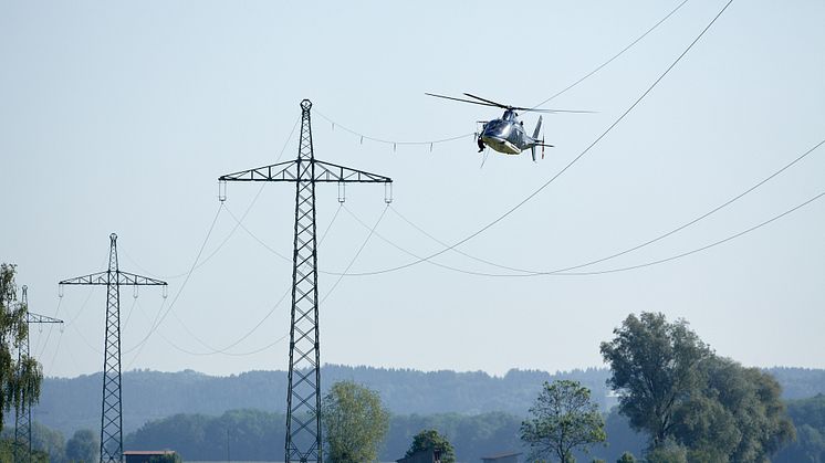 Vom Hubschrauber aus hat ein Monteur im Abstand von rund 25 Metern die Vogelschutzmarker am obersten Blitzschutzseil der Freileitung angebracht.