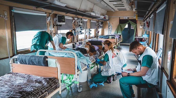 Personal på intensivvårdsavdelningen på Läkare Utan Gränsers tåg övervakar och stabiliserar en svårt krigsskadad patient under en resa från Pokvrosk i östra Ukraina till Lviv i västra Ukraina. Resan tar ungefär 20 timmar. Foto: Andrii Ovod. 