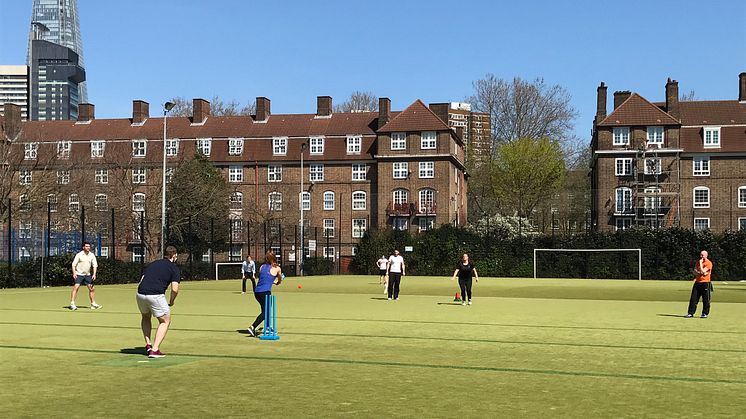 People playing cricket on an outdoor astro pitch in Southwark, with the Shard in the background