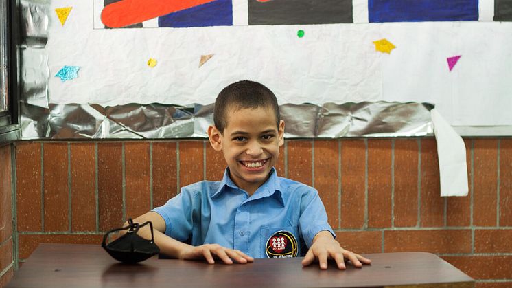 Juan Pablo, 12, från Venezuela sitter och ler vid sin skolbänk.