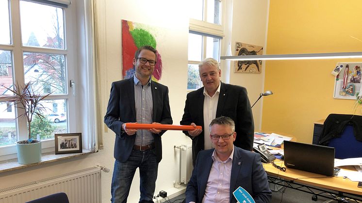 Bürgermeister Andreas Wittenberg hat einen Vertrag für einen echten, kupferfreien Glasfaseranschluss unterzeichnet. Dahinter: Tjark Hartmann (links) und Stefan Teutscher von Deutsche Glasfaser.
