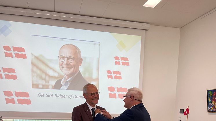 På billedet får kommunaldirektør Ole Slot sat ordenen Ridder af Dannebrog på reversen af borgmester Frank Schmidt-Hansen.