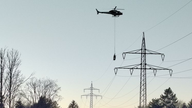 Arbeiten in luftigen Höhen: Für eine sichere Stromversorgung arbeiten Monteure in einem Korb, der an einem Hubschrauber hängt, an der Reparatur kleiner Schäden an Hochspannungsleitungen. 