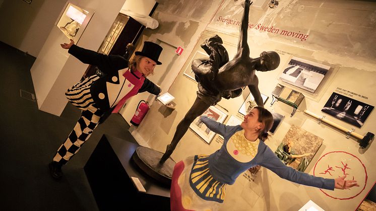 Proffsdansarna från Svenska Baletten Jean Börlin och Ebon Strandin besöker Dansmuseet och härmar de utställda föremålen. Här övar de tåspetsdans efter en staty som föreställer Galina Ulanova.
