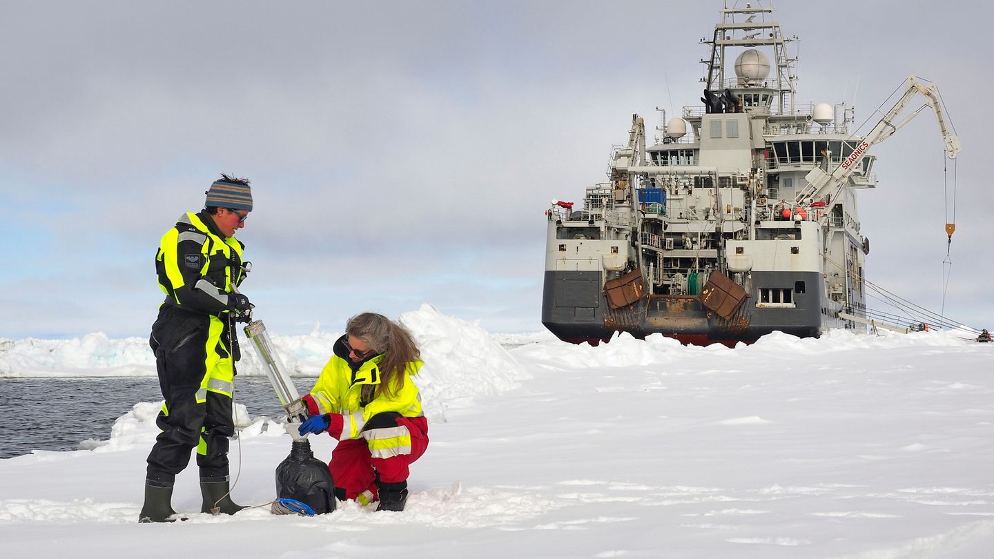 Eva Leu og Angelika Renner tar vannprøver i Polhavet på jakt etter isalger. I bakgrunnen forskningsskipet Kronprins Haakon. (Foto: Ann Kristin Balto / Norsk Polarinstitutt)