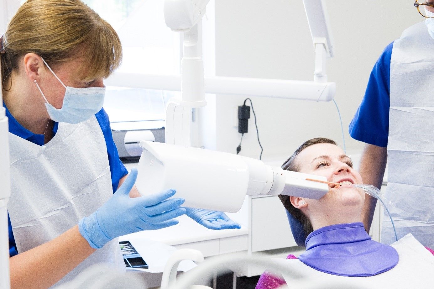 Tandvårdpersonal tar en röntgenbild av en kvinnlig patient.