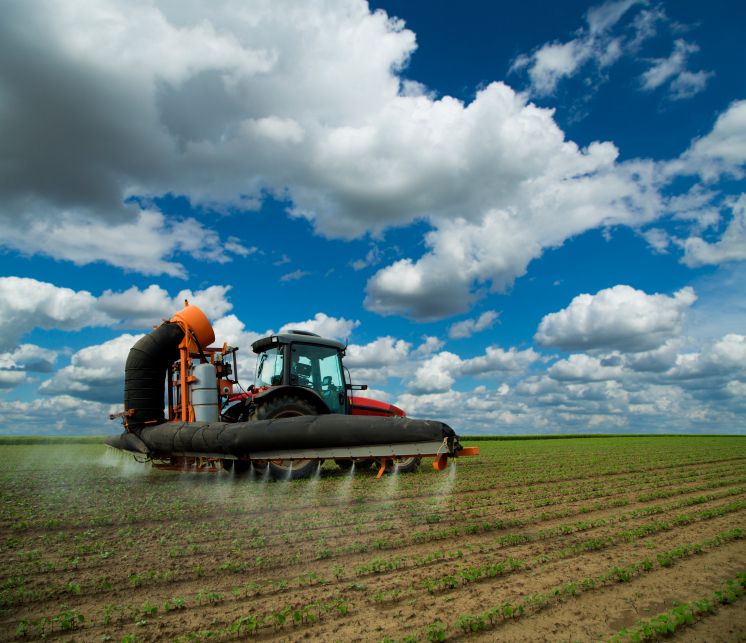 Tractor spraying soybean crops field at spring season, often using herbicides, which may leech through the soil into water sources below and possibly end up in human or animal drinking water.