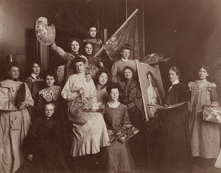 Harriet Backer med noen av elevene sine. Backer er i midten av bildet, til venstre for lerretet. Ca. 1905.