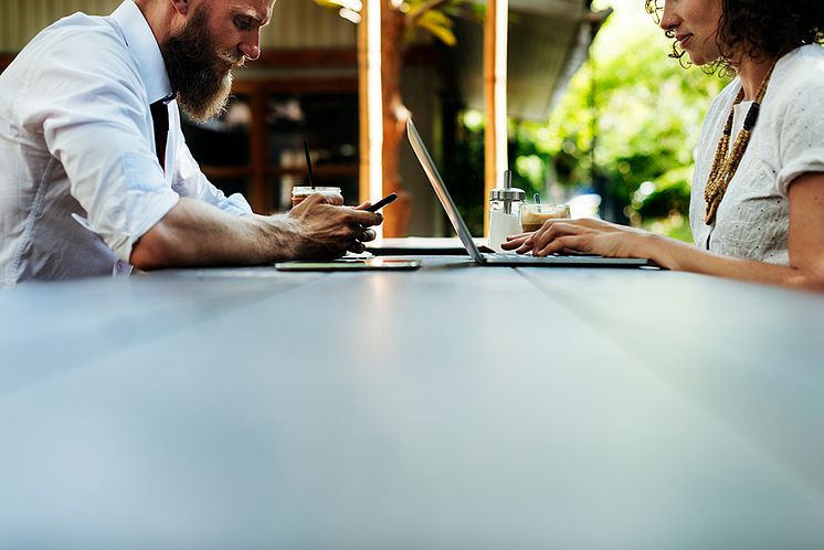 Mann og kvinne som bruker laptop og mobil paa cafe